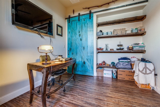 home office featuring a barn door, dark wood-style flooring, and baseboards