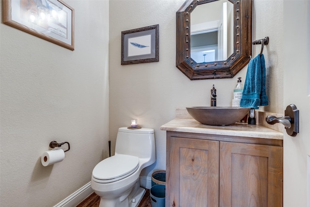 bathroom featuring baseboards, vanity, and toilet