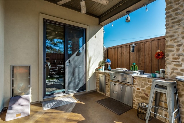 view of patio / terrace with exterior kitchen, fence, and a bar