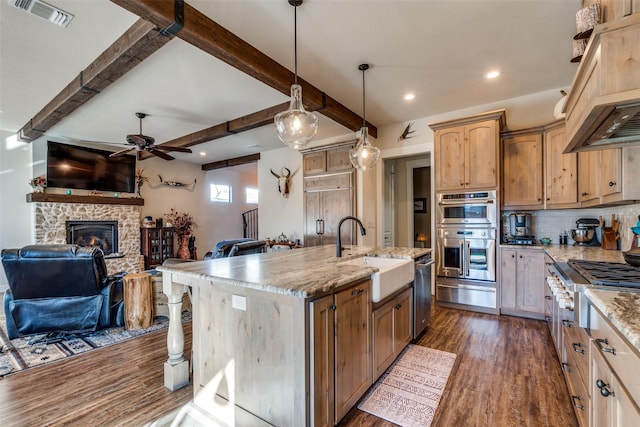 kitchen with a center island with sink, stainless steel appliances, visible vents, open floor plan, and a sink