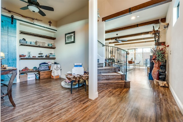 interior space with a barn door, baseboards, wood finished floors, stairs, and beam ceiling