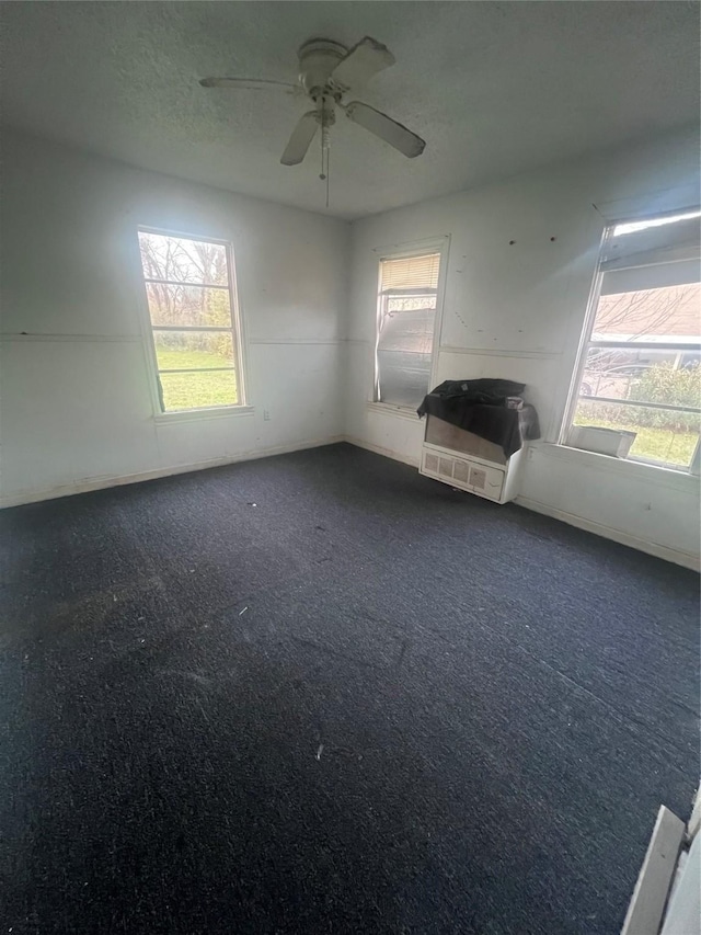 unfurnished room featuring dark colored carpet, plenty of natural light, and a textured ceiling