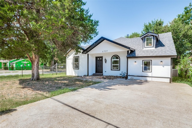 view of front of home with driveway, roof with shingles, and fence