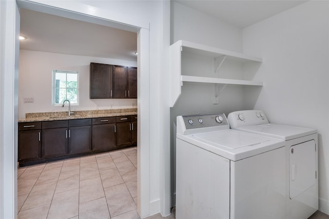 clothes washing area with independent washer and dryer, a sink, and light tile patterned floors