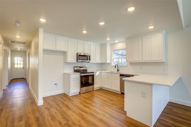 kitchen with light wood-style flooring, visible vents, white cabinetry, light countertops, and appliances with stainless steel finishes