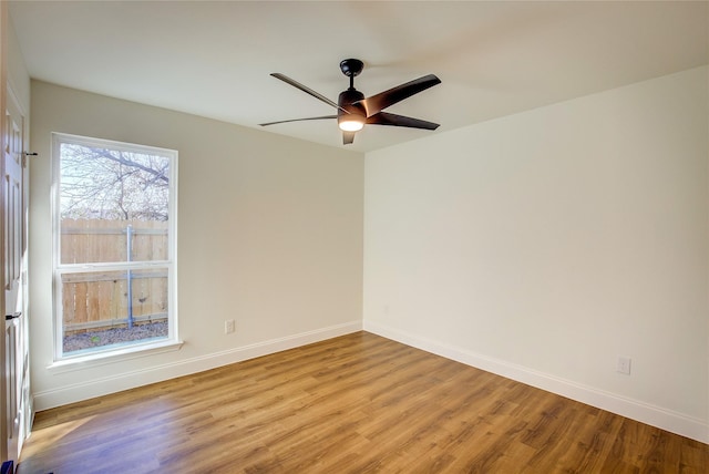 spare room with light wood-type flooring, ceiling fan, and baseboards