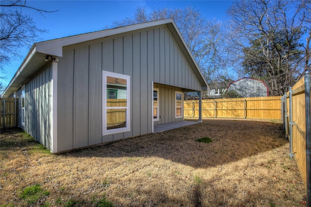 rear view of house featuring a yard, board and batten siding, and a fenced backyard