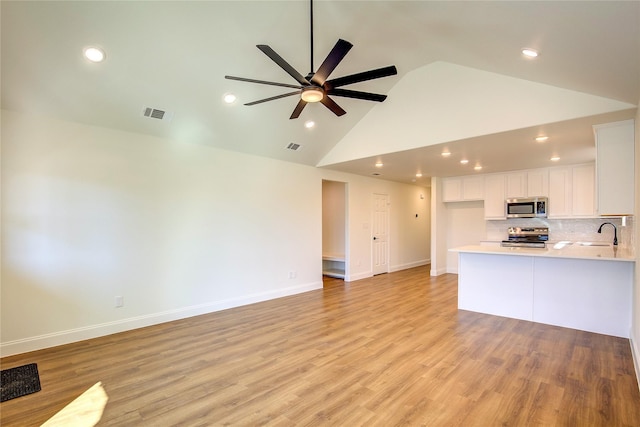 interior space with baseboards, light wood-style flooring, visible vents, and a sink