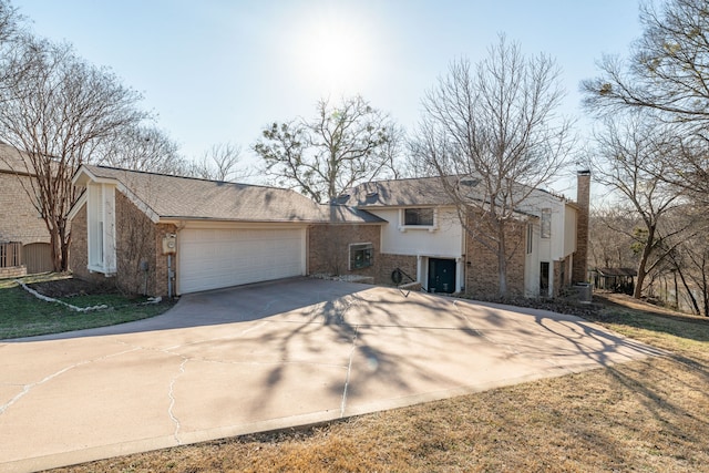 view of front of house featuring driveway, brick siding, an attached garage, and cooling unit