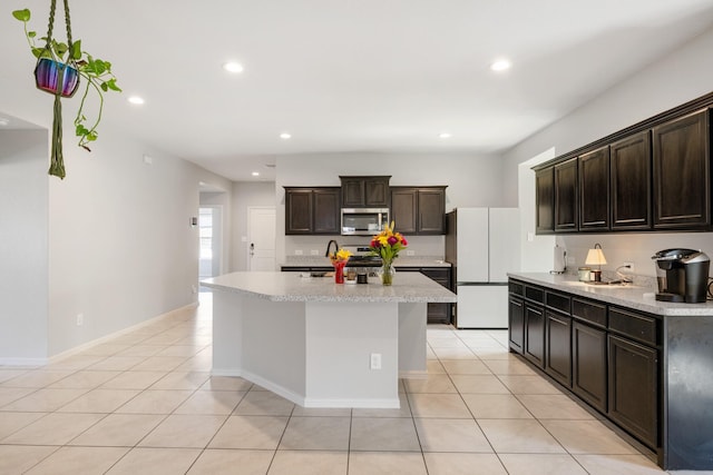 kitchen featuring light tile patterned floors, a center island with sink, stainless steel appliances, and light countertops