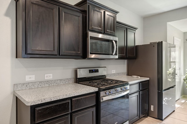 kitchen with dark brown cabinetry, light tile patterned floors, stainless steel appliances, and light countertops