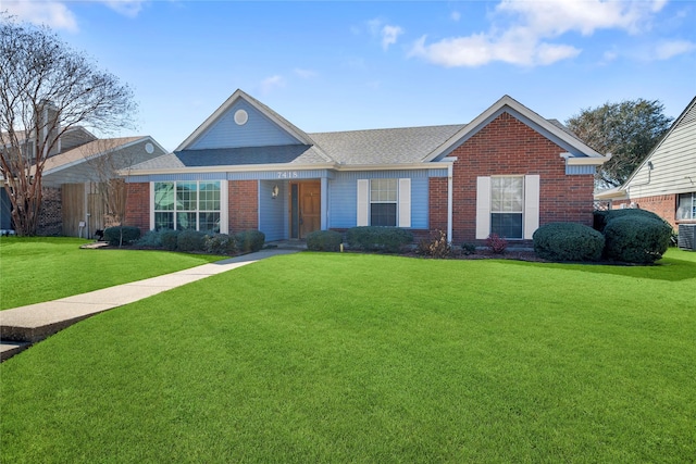 ranch-style home with brick siding, a front yard, cooling unit, and a shingled roof