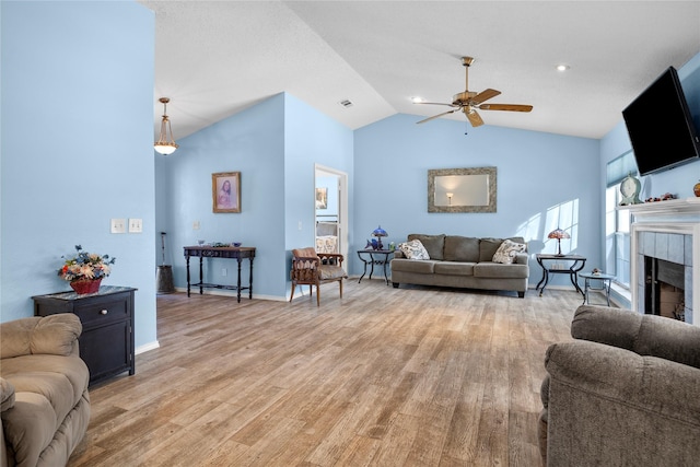 living area with ceiling fan, a fireplace, visible vents, baseboards, and light wood-type flooring