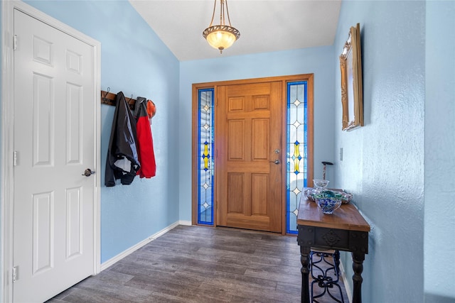 foyer entrance with dark wood-style floors, baseboards, and a textured wall