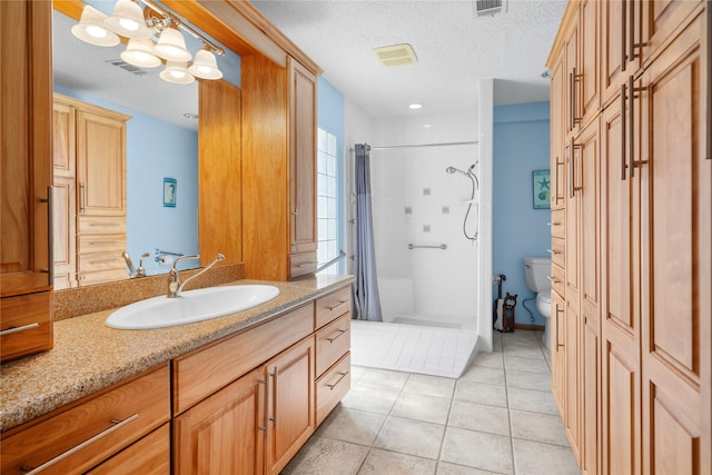 bathroom with a textured ceiling, toilet, vanity, visible vents, and a shower stall