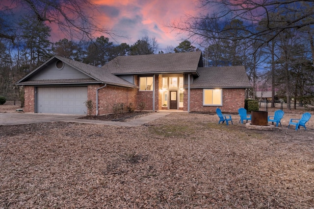 view of front of property featuring a fire pit, driveway, brick siding, and a garage