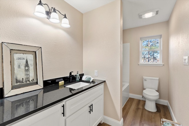 bathroom with baseboards, visible vents, toilet, wood finished floors, and vanity