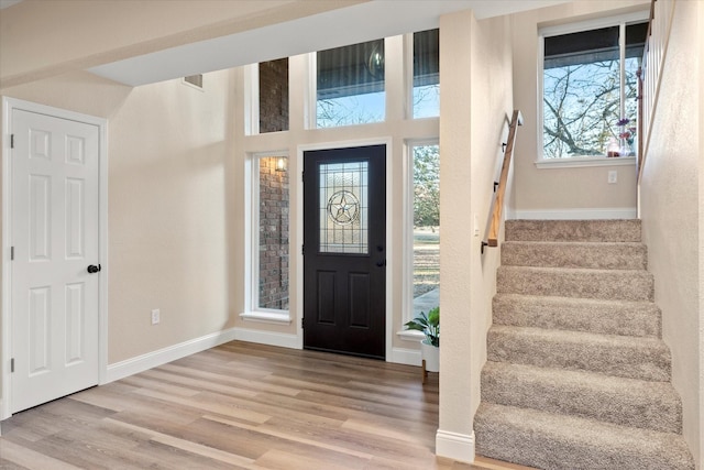 entryway with stairs, light wood-type flooring, and baseboards