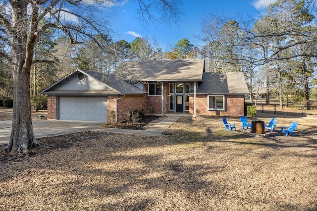 view of front of property featuring an outdoor fire pit, concrete driveway, brick siding, and an attached garage