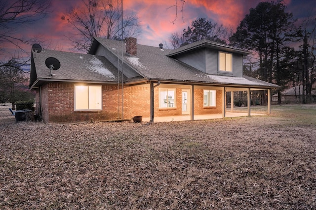 back of house with a patio, brick siding, a chimney, and a shingled roof