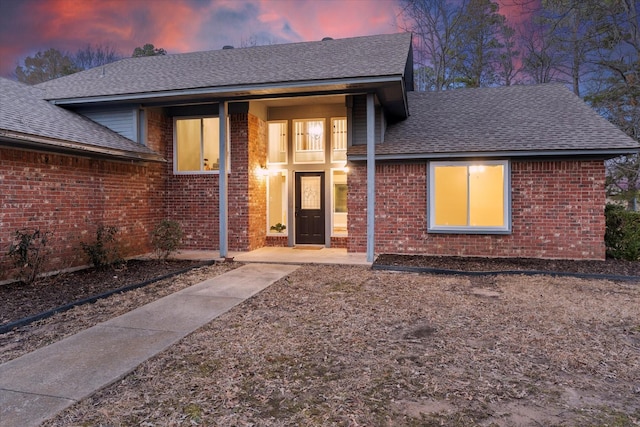 view of front facade featuring brick siding and a shingled roof