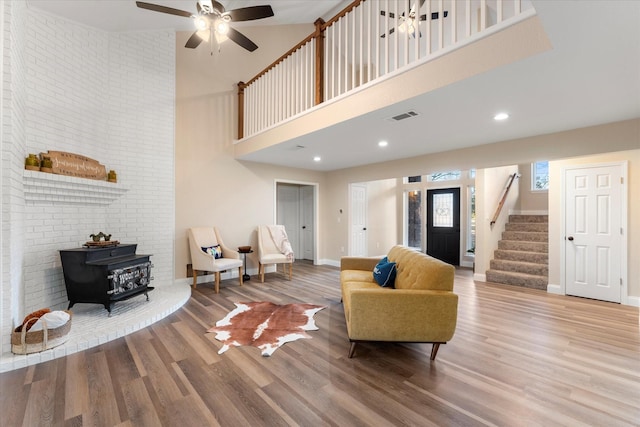 living area with visible vents, stairway, a wood stove, wood finished floors, and baseboards