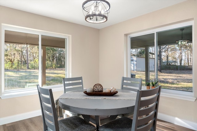 dining room with baseboards, wood finished floors, and an inviting chandelier