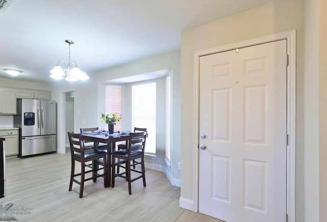 dining space with a notable chandelier, baseboards, visible vents, and light wood-style floors