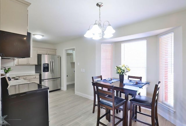 dining space featuring light wood-style floors, baseboards, and a chandelier