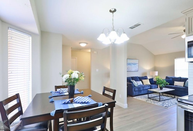 dining space with a chandelier, visible vents, baseboards, vaulted ceiling, and light wood-type flooring