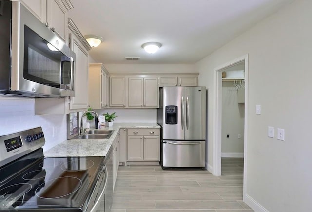 kitchen featuring stainless steel appliances, wood finish floors, a sink, visible vents, and decorative backsplash