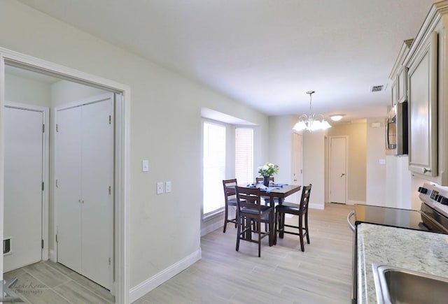 dining space featuring light wood-type flooring, baseboards, and an inviting chandelier