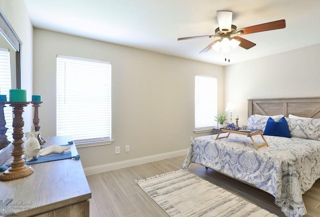 bedroom featuring a ceiling fan, light wood-style flooring, and baseboards