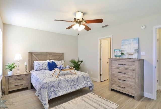 bedroom with baseboards, visible vents, a ceiling fan, and wood finish floors