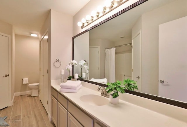 bathroom featuring curtained shower, toilet, wood finished floors, vanity, and baseboards