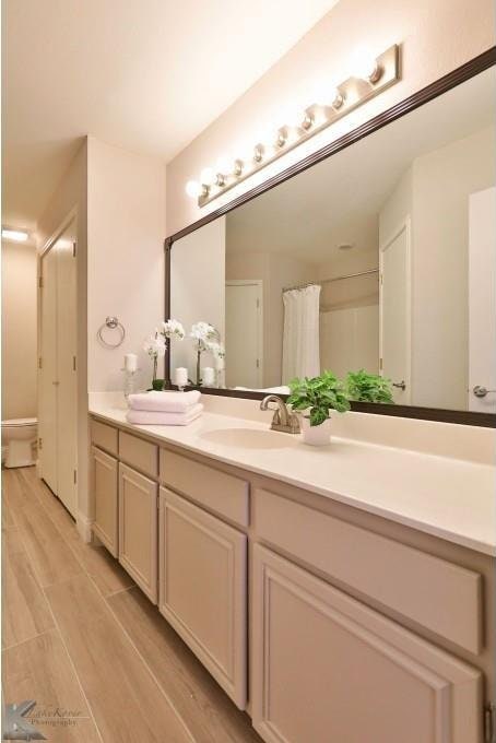 bathroom with a shower with shower curtain, wood finished floors, and vanity