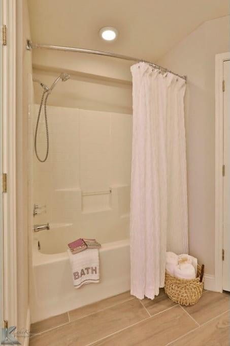 bathroom with wood finish floors and shower / tub combo with curtain