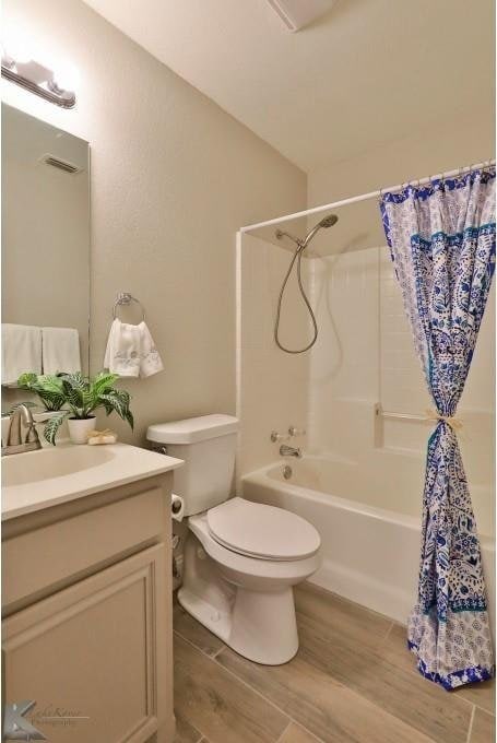 full bathroom with toilet, wood finished floors, visible vents, vanity, and shower / tub combo with curtain