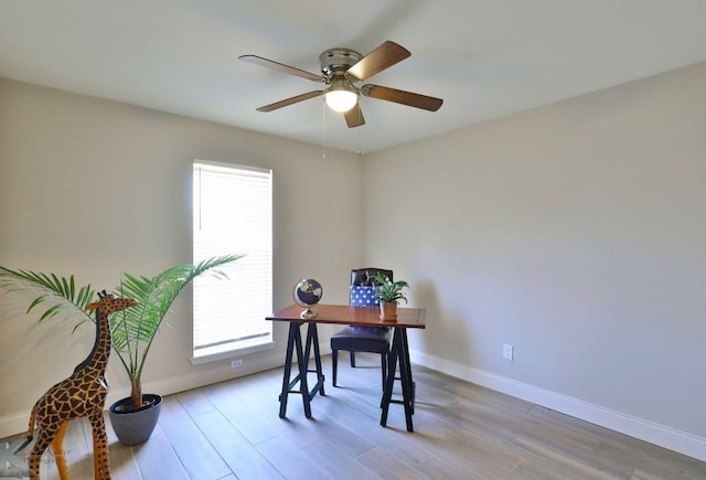 office area with a ceiling fan, light wood-style flooring, and baseboards