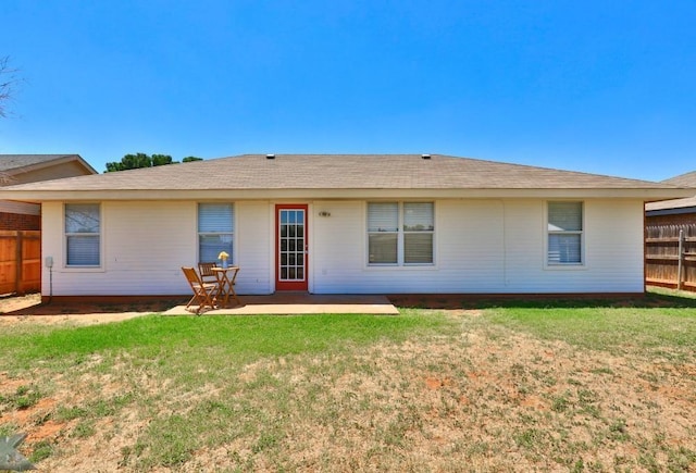 rear view of house with a patio, a yard, and fence