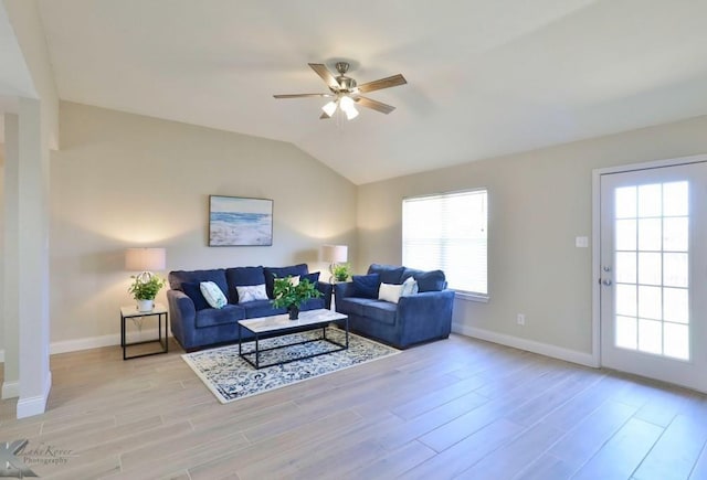 living area with light wood-style floors, vaulted ceiling, baseboards, and a ceiling fan