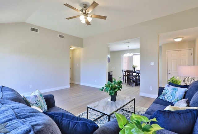 living room featuring baseboards, visible vents, light wood finished floors, and ceiling fan with notable chandelier