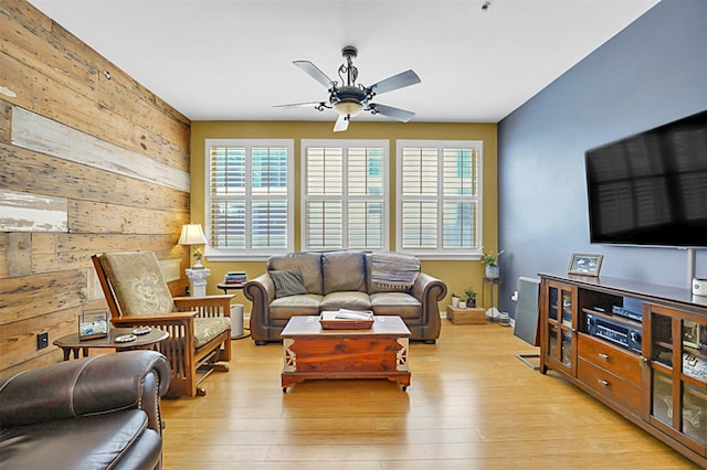 living area with a healthy amount of sunlight, light wood-style flooring, and wooden walls