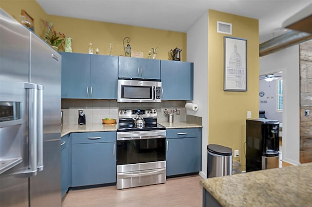 kitchen with stainless steel appliances, visible vents, light countertops, blue cabinetry, and backsplash