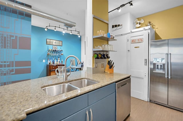 kitchen featuring light wood finished floors, appliances with stainless steel finishes, light stone counters, a sink, and track lighting