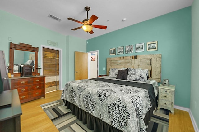 bedroom featuring baseboards, visible vents, ceiling fan, and wood finished floors