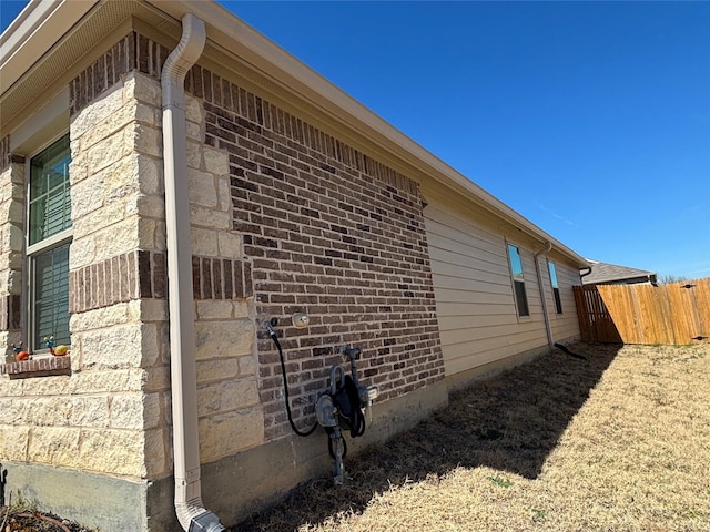 view of home's exterior featuring brick siding and fence