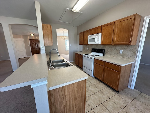 kitchen with white appliances, arched walkways, light countertops, and a sink