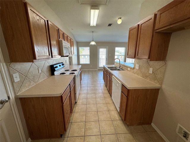 kitchen featuring white appliances, light tile patterned floors, decorative light fixtures, light countertops, and a sink