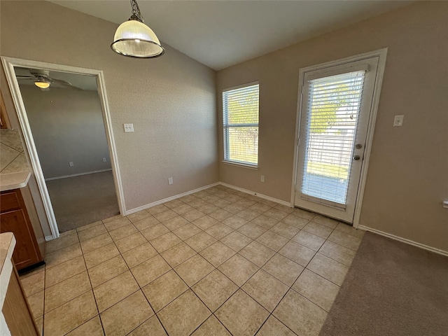 unfurnished dining area with light carpet, light tile patterned floors, vaulted ceiling, and baseboards